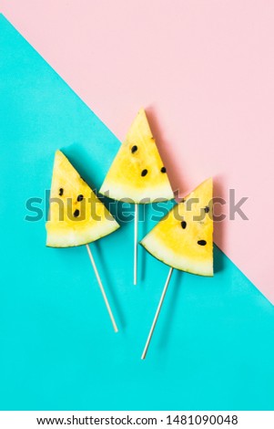 three triangular ice cream slices on a stick of ripe yellow watermelon