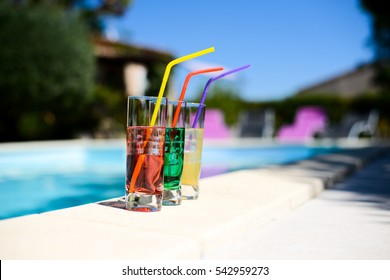 Three Tropical Colorful Drink Cocktail With A Straw On The Poolside Of Resort Swimming Pool With Nobody