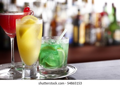 Three Tropical Mixed Drinks Sitting On Silver Tray, Shot In Bar With Space For Copy