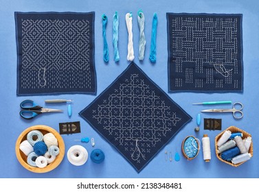 Three types of geometric embroidery in style of Sashiko with white threads on blue cotton fabric with intricate patterns. Accessories for embroidery on blue background. Needlework as hobby. Flat lay