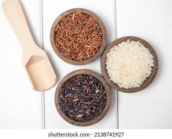 Three types of rice in wooden bowls on a white wooden table. red ,black and white rice ,copy space