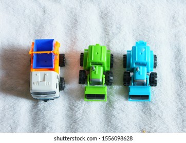 three types of toy vehicles, garbage truck, and two unit tractors green and blue 