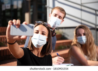 Three University Students Wearing Face Masks Taking A Selfie During Coronavirus Or Covid-19 Pandemic.