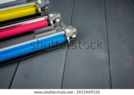 Three used toner cartridges in a color laser printer on gray wooden background for recycling