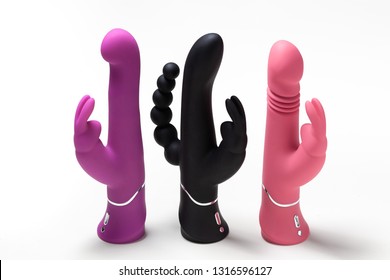 Three vaginal dildo in the form of a rabbit stand on a white background. Sex toys for adults. Above view. Place for text. Sex shop concept. Multi-colored vibrators