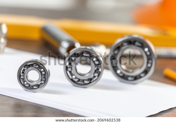 Three various ball bearings lying on paper
sheet. Heavy industry engineering company. Automotive designing and
manufacturing. Spare parts for machinery. Steel details for engine
mechanisms.