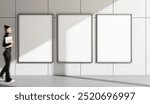 Three vertical blank posters on a grey tiled wall, a woman walking by holding a notepad. Modern design, concept of advertising, empty template