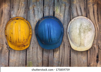 Three vintage construction helmets hanging on an old wooden wall