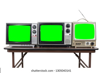 Three vintage televisions on wood table isolated on white with chroma key green screens.