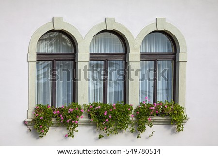 three vintage windows with stone frames and flowers on shelf