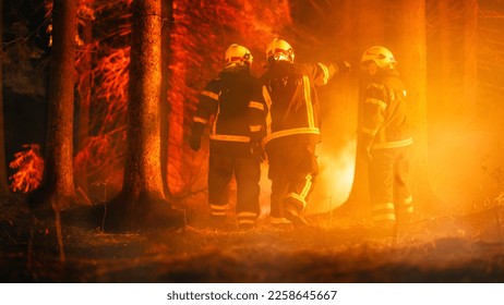 Three Volunteer Firefighters with Safety Equipment and Uniform Encircle a Raging Forest Fire Before the Blaze Gets Completely Out of Hand. Firemen Respond to Emergency and Prevent a Disaster. - Shutterstock ID 2258645667