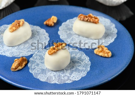  three walnut cameo decorated with a walnut on a blue plate on a reflective dark background