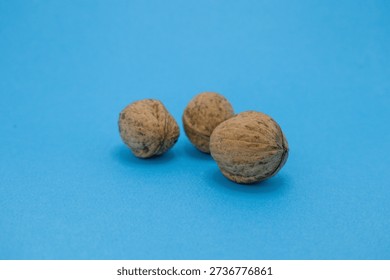 Three walnuts are displayed on a blue surface, showcasing their texture and natural color.