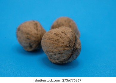 Three walnuts are displayed on a blue surface, showcasing their texture and natural color.