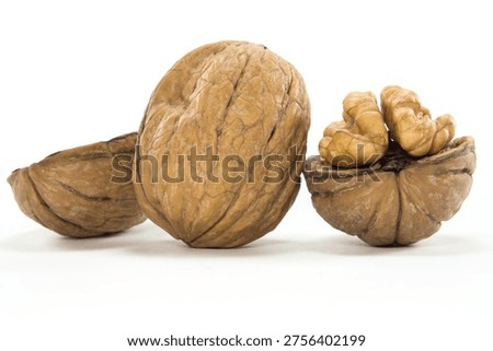 Three walnuts on white background â€” one whole, one open shell, one cracked revealing the kernel inside.
