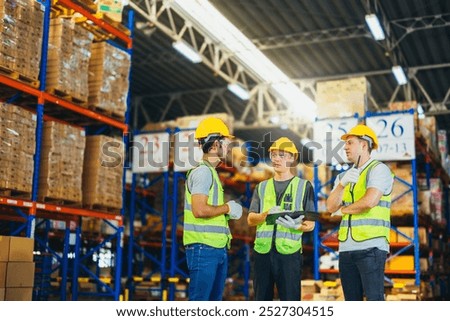 Three warehouse workers using a digital tablet while recording inventory. Logistics employees working with warehouse management software in a large distribution centre.