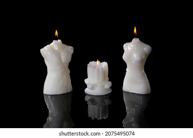 Three white candles, burning on black background. candles in the shape of an antique column and a torso of a man and a woman - Powered by Shutterstock