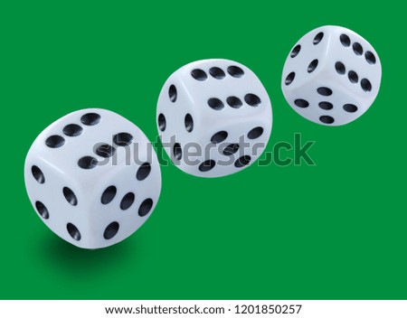 Three white dices of different size thrown in a craps game, yatzy or any kind of dice game against a green background 