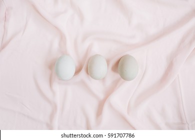 Drei weiße Ostereier auf rosafarbenem Stoffhintergrund. Flachlage, Draufsicht. – Stockfoto