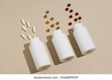 Three white mockup jars with scattered pills capsules diagonally on a beige isolated background. the concept of pharmacy, medical drugs and dietary supplements. Image for your design