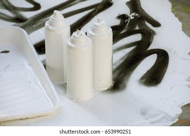 Three white paint cans sitting on graffiti