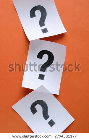 Three white paper notes with question marks arranged vertically on orange background