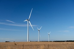 Three Wind Turbines On A Farm In An Australian Landscape.