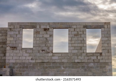 Three window openings in exterior concrete wall of a single-family house under construction on a cloudy evening in southwest Florida