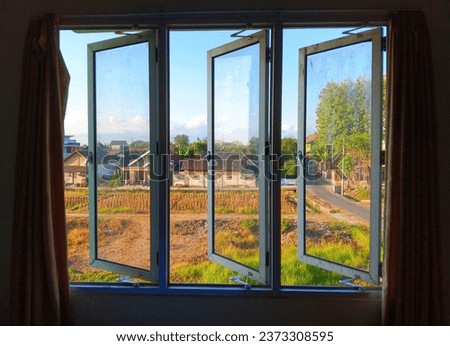three window shutters made of aluminum and the same frame, opened at the same angle to reveal the view outside and circulate air in the room.