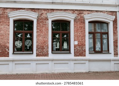 Three windows with brown frames on red brick building facade