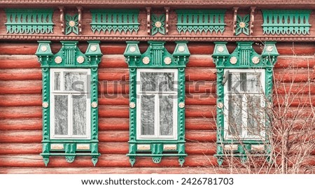 Three windows with carved wooden decorations and architraves on facade of 19th century log house . Nizhny Novgorod region, Russia. Architecture concept