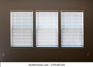 Three Windows With Closed Modern White Wood Faux Window Blinds As Background.