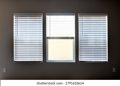 Three Windows With Closed Modern White Wood Faux Window Blinds As Background.