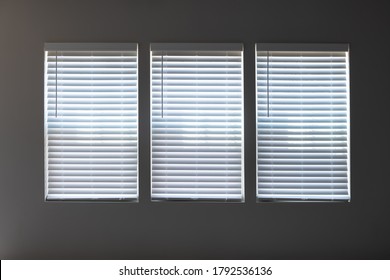 Three Windows With Closed Modern White Wood Faux Window Blinds As Background.