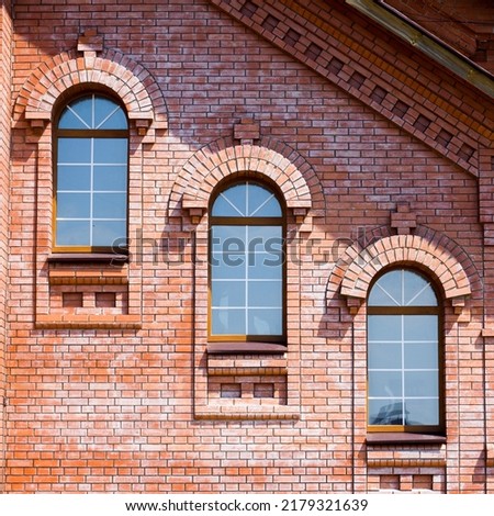 Three windows diagonally across a red brick wall
