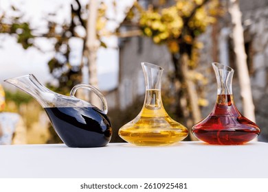 Three wine glasses are on a table, one of which is red. The other two are yellow and clear