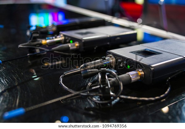 Three wireless\
microphone transmitter and three wireless microphone reciever on\
black table in tv studio