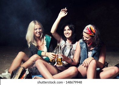 three woman drinks beer on the beach