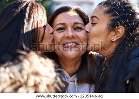 Three woman mother and daughters standing together and kissing at park