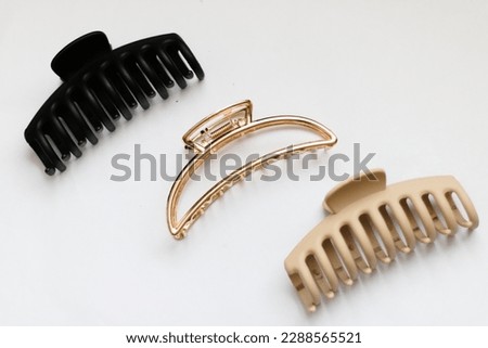 Three woman's hair accessories. Claw clips. Trendy hairstyle. Trendy accessory. Fashionable accessory. Metal claw clip. Plastic claw clip. Gold claw clip. 