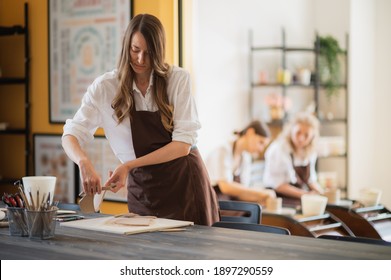 Three women in aprons working at pottery, kneading clay and making earthenware at workshop - Shutterstock ID 1897290559