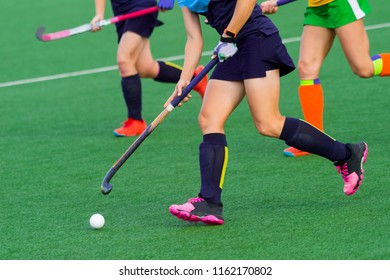 Three Women Battle For Control Of Ball During Field Hockey Game