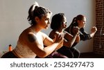 Three women exercising indoors, focusing on fitness. Diverse group in workout attire, practicing squats. Sunlit room, emphasizing strength and concentration. Healthy women exercising at fitness gym.