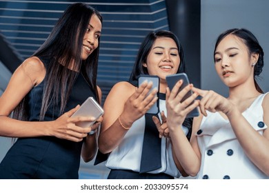 Three Women Friends Having Conversation While Looking At Mobile Phone In Their Hands. Concept Of Social Media, Gossip News And Online Shopping.