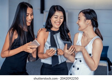 Three Women Friends Having Conversation While Looking At Mobile Phone In Their Hands. Concept Of Social Media, Gossip News And Online Shopping.