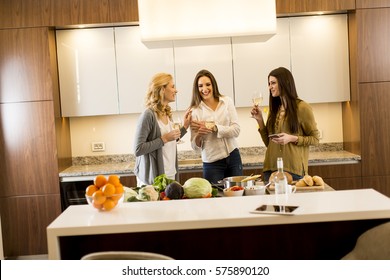 Three Women Friends Toasting White Wine In Modern Kitchen