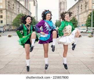 Three women in irish dance dresses dancing outdoor