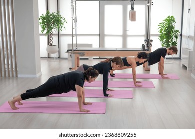 Three women and a man are doing plank exercises. Group yoga. - Shutterstock ID 2368809255