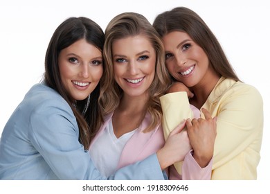 Three Women In Pastel Suits Posing Over White Background