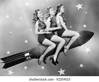 Three women sitting on a rocket